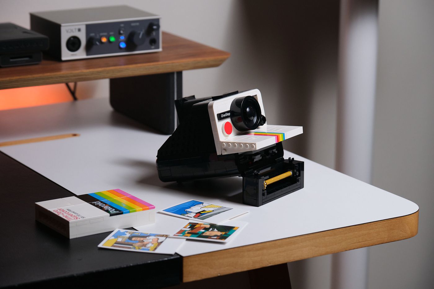 The Lego Ideas Polaroid OneStep in final prototype form, with its film bay open, sitting alongside its brick-built film box and photocards.